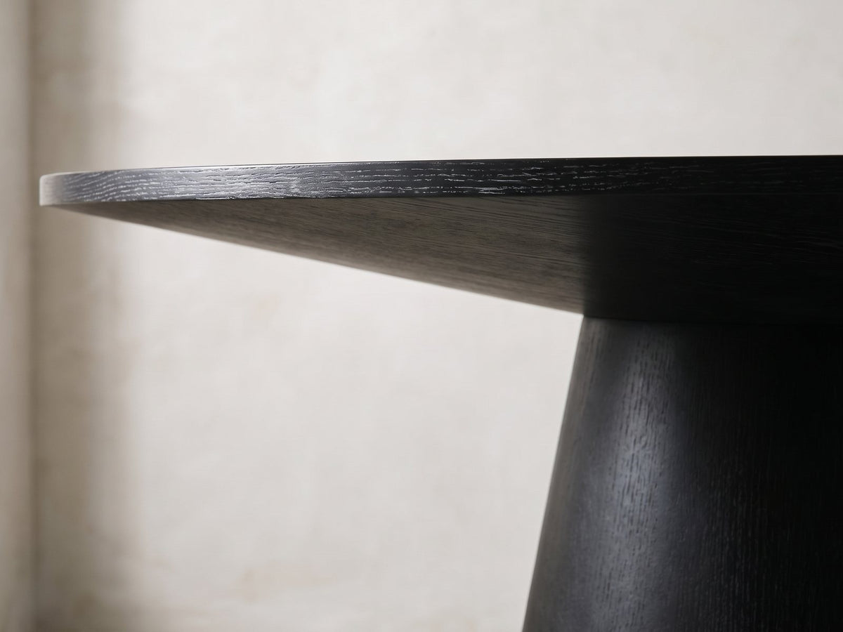 Close-up of the Sellia 59-Inch Round Ebony Cone Pedestal Dining Set with 4 Chairs: the slim edge and sloped underside of the round top over the cone pedestal