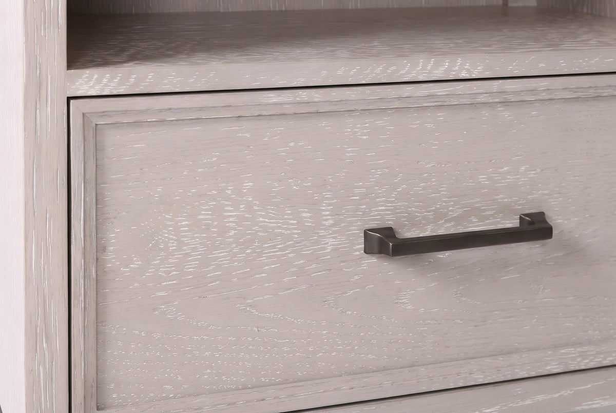 The drawer of the Sennori nightstand: a slim dark bronze bar pull on cerused oak with a narrow stepped border