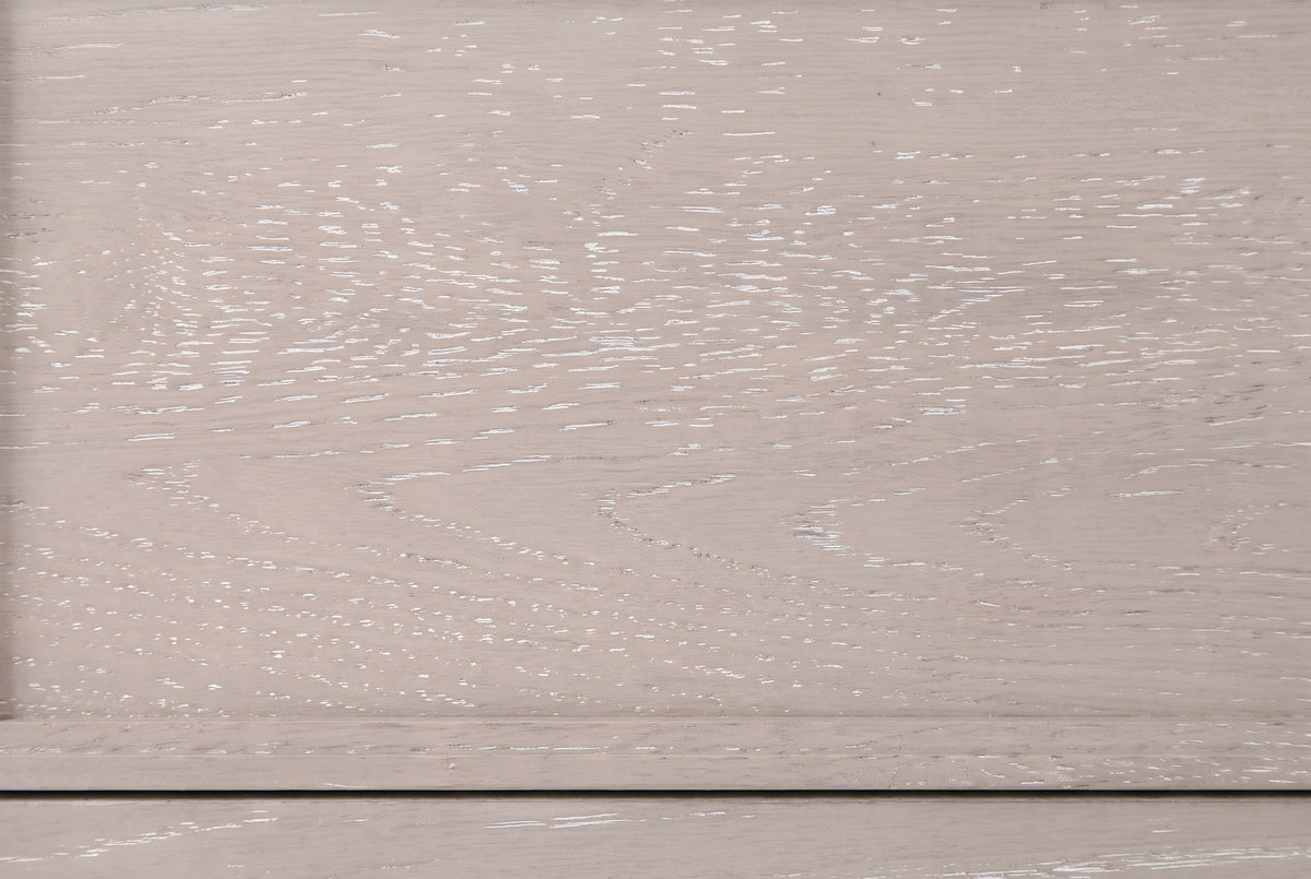 Close-up of the cerused oak on the Sennori nightstand: pale greige wood with white-filled grain and the narrow stepped drawer border
