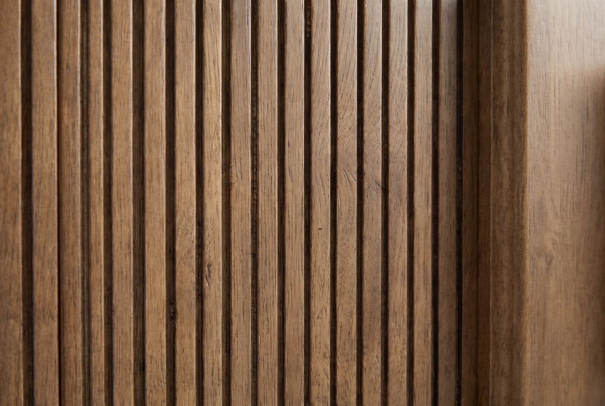 Close-up of the reeded drawer front of the Senorbi nightstand: narrow vertical ribs in warm ash brown beside the plain centre strip
