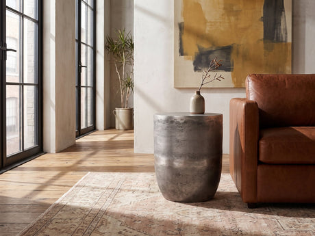 Sepino Antique Silver Metal Drum Side Table beside the arm of a cognac leather seat in an industrial loft