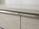 Close-up of the Sesto 63-Inch Gray Oak 6-Drawer Dresser: the brushed steel edge pulls meeting at the centre seam