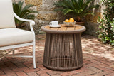 Siculiana rope side table with a coffee cup and a bowl of oranges beside a white armchair in a St. Augustine courtyard, a coquina stone wall and red brick pavers (chair and decor not included)