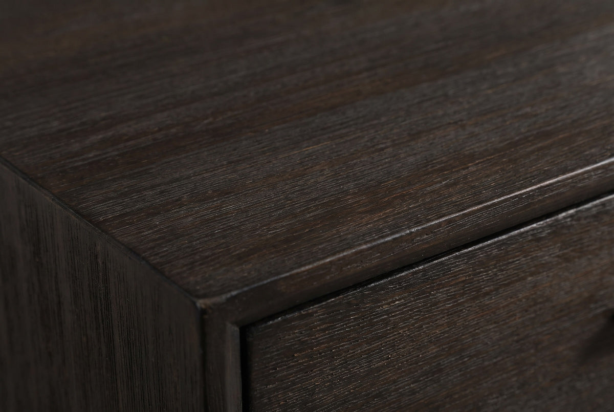 Close-up of the dark wire-brushed acacia on the Siniscola nightstand: the top edge and the frame around the drawer