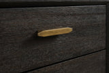 The upper drawer of the Siniscola nightstand: a slim antique-brass bar pull with faceted ends on dark wire-brushed acacia