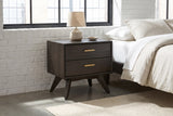 Siniscola dark acacia nightstand with a ceramic lamp against a white-painted brick wall in a Denver loft bedroom with a concrete floor