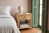Sinnai rattan nightstand against a blush pink plaster wall in a New Orleans bedroom with green shutters