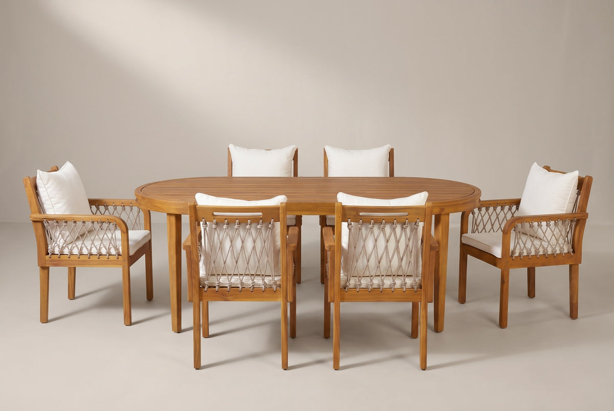 The Siracusa 7-piece dining set: an acacia oval table and six rope armchairs with ivory cushions on a light studio backdrop
