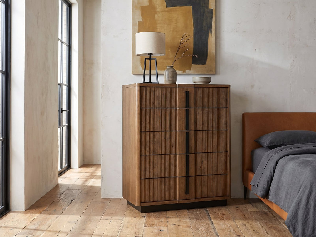 Soave 40-Inch Ash Brown Reeded 5-Drawer Chest against a plaster wall in an industrial loft bedroom
