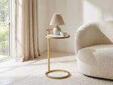 Soleto White Marble Ring-Base Side Table with a lamp and a ceramic bowl beside a cream boucle armchair in a bright plaster room