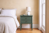 Sorgono green faux-bamboo nightstand against a butter-yellow plaster wall in a Charleston bedroom with heart-pine floors