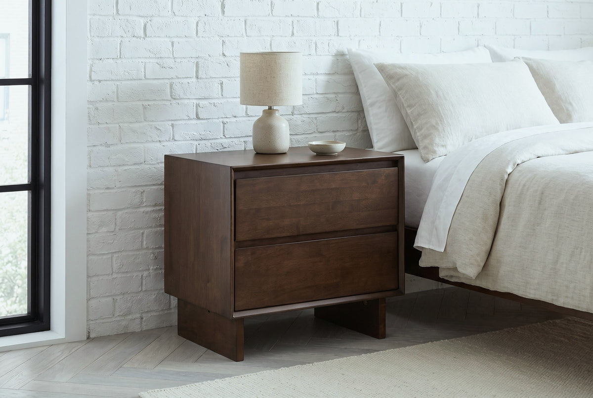 Sorso warm brown nightstand with a ceramic lamp against a whitewashed brick wall in a Brooklyn bedroom