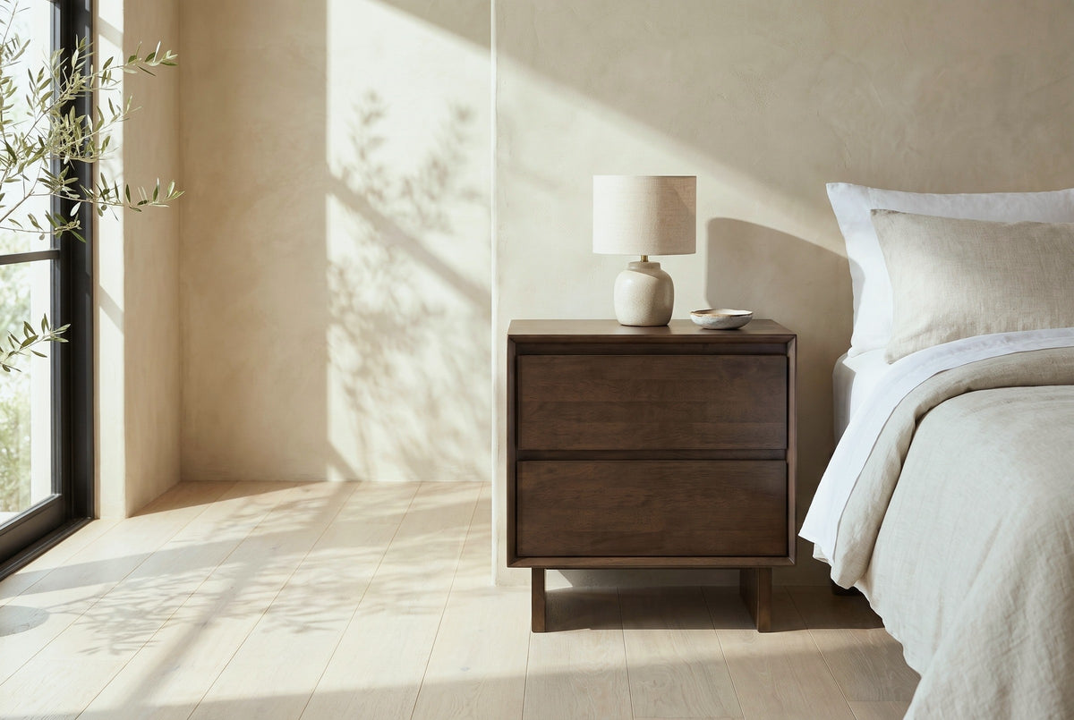 Sorso warm brown solid wood nightstand with a ceramic lamp beside a bed in a Santa Barbara bedroom with a sand-coloured plaster wall