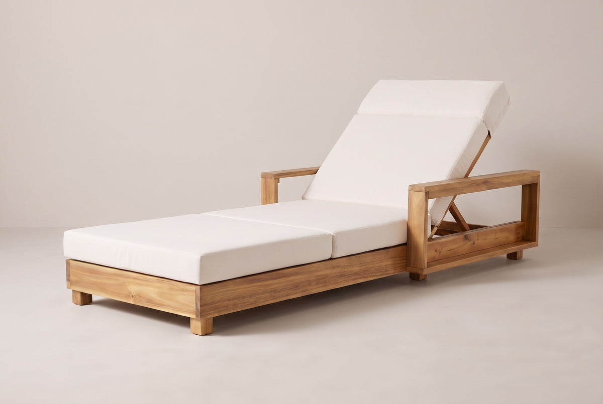 The Sortino acacia chaise lounge with a cream cushion, three-quarter view from the foot end on a light studio backdrop