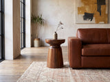 Specchia Brown Mango Cone Pedestal Side Table beside a leather sofa in an industrial loft