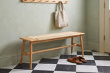 Sperlonga oak bench with a paper cord seat along a sage-green plaster wall in a Charleston townhouse entry, with a wooden peg rail, a linen tote bag and a black and white marble floor (bag and shoes not included)