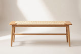 The Sperlonga bench, straight view of the long side on a light studio backdrop: the oak end blocks, the cord seat, four tapered legs and the long round rail