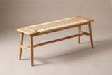 The Sperlonga bench in natural oak with a woven paper cord seat between two oak end blocks, three-quarter view on a light studio backdrop