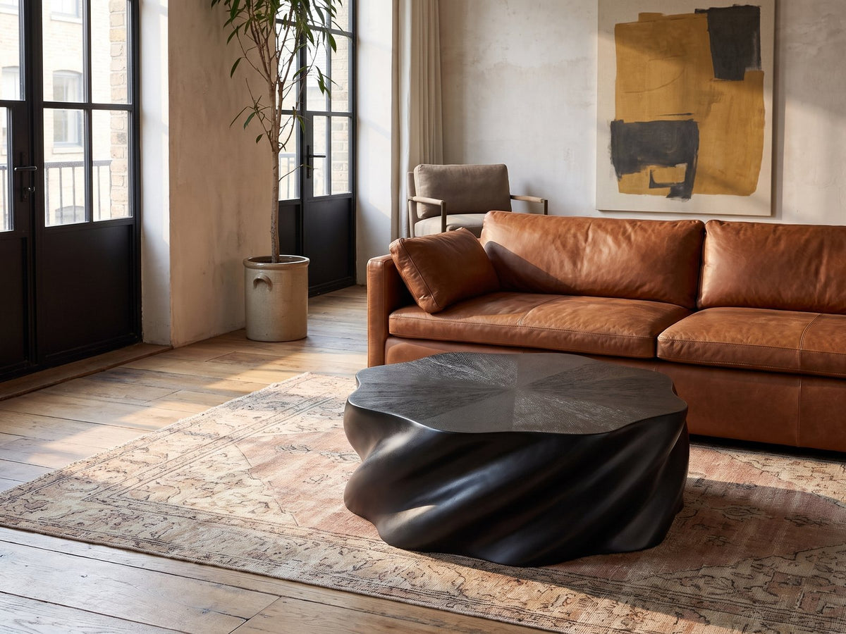 Spilimbergo Black Fiberglass Twisted Petal Coffee Table on a vintage rug in front of a leather sofa in an industrial loft