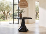 Spilimbergo Black Fiberglass Twisted Petal Pedestal Dining Table in a sunlit villa dining area with olive trees outside