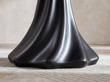 Close-up of the Spilimbergo Black Fiberglass Twisted Petal Pedestal Dining Table: the twisted black ridges of the pedestal flaring into its lobed foot