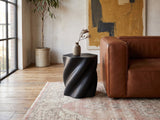 Spilimbergo Black Fiberglass Twisted Petal Side Table beside a leather sofa in an industrial loft