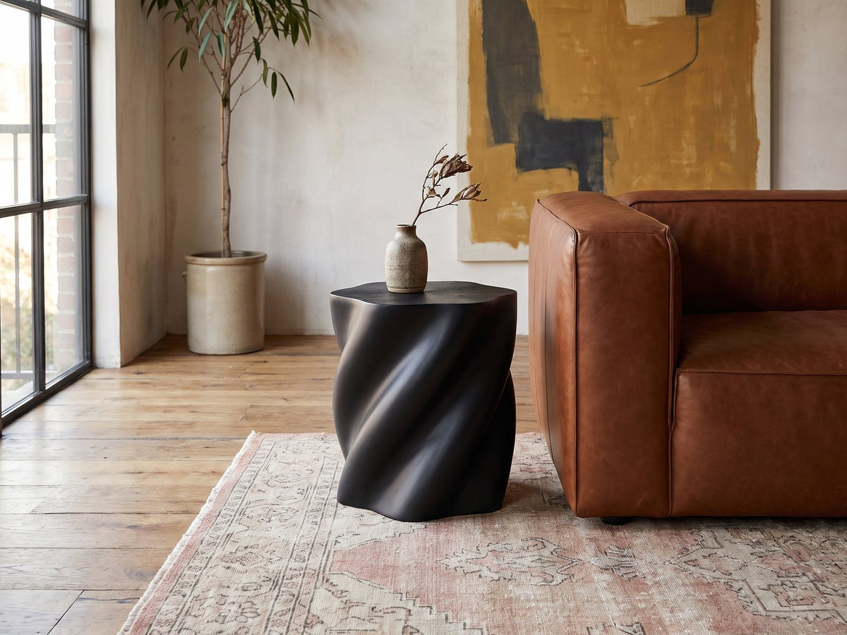Spilimbergo Black Fiberglass Twisted Petal Side Table beside a leather sofa in an industrial loft