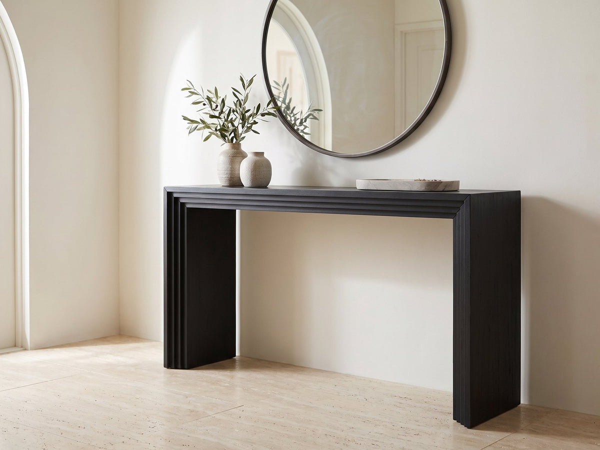 Spinazzola Black Paulownia Waterfall Console Table under a round mirror in a travertine entryway