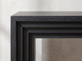 Close-up of the Spinazzola Black Paulownia Waterfall Console Table: the mitred front corner with its stepped, layered edge