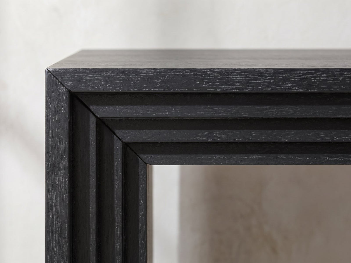 Close-up of the Spinazzola Black Paulownia Waterfall Console Table: the mitred front corner with its stepped, layered edge