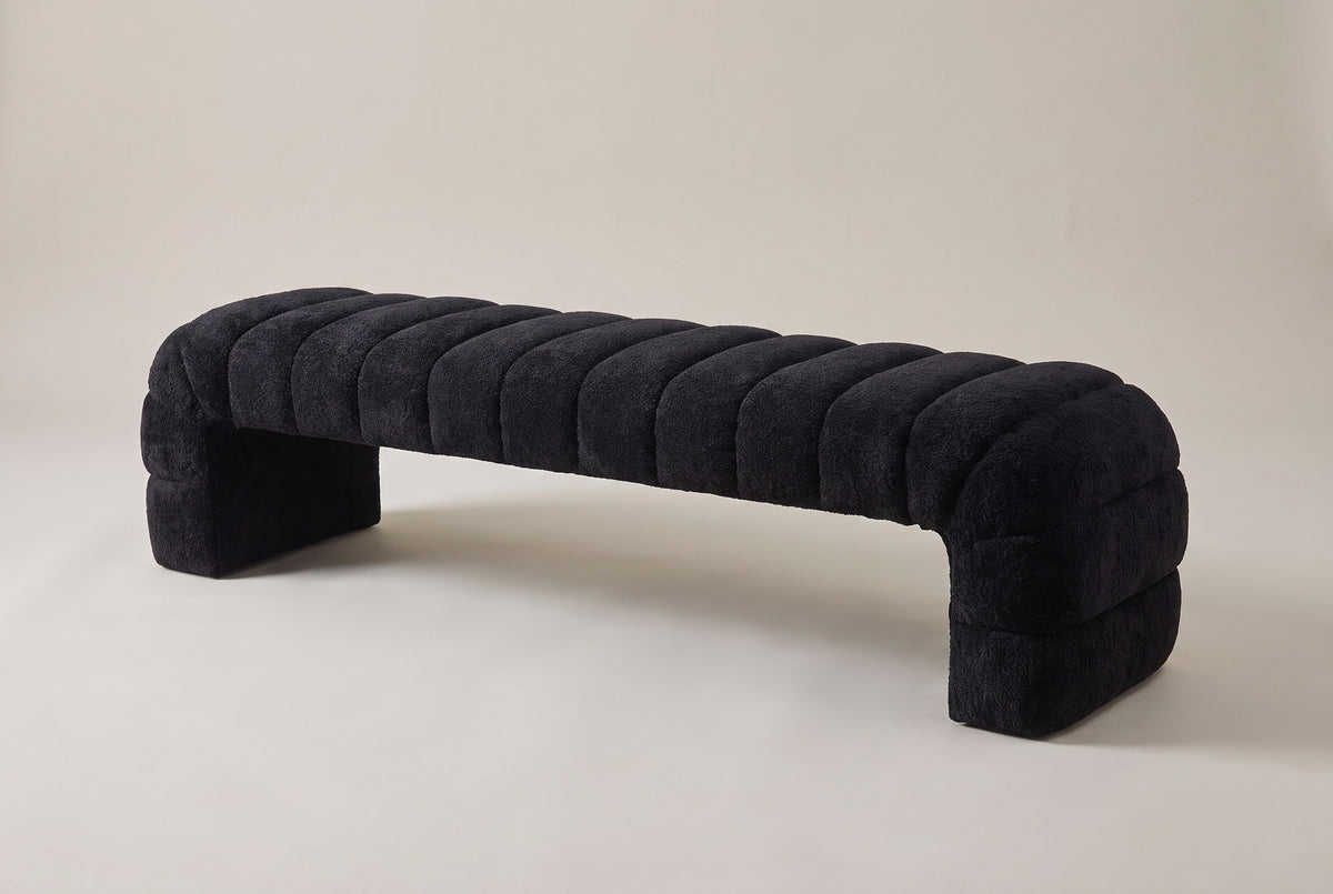 The Spoleto bench in black chenille, three-quarter view on a light studio backdrop: a row of channels with a rolled end channel at each end