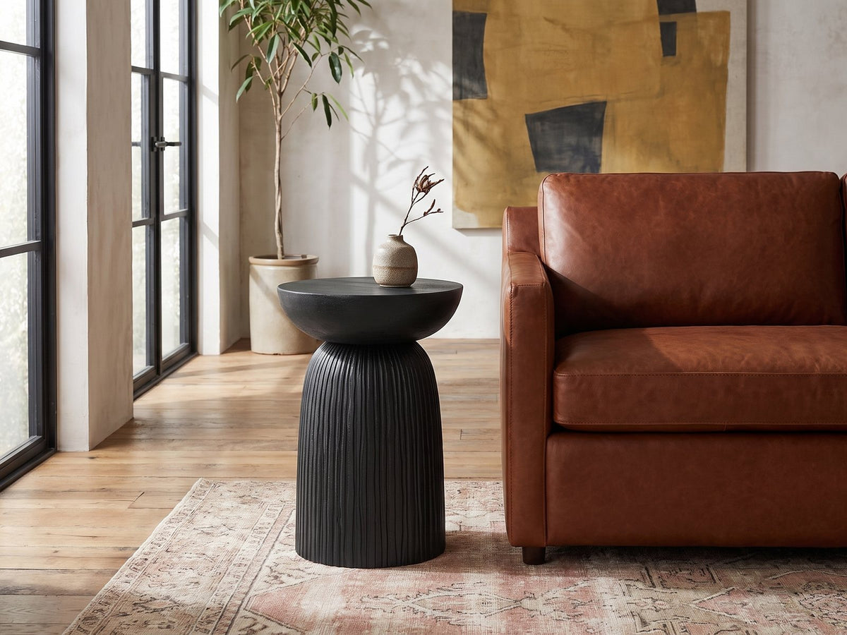 Stigliano Black Mango Bell Pedestal Side Table beside a leather sofa in an industrial loft