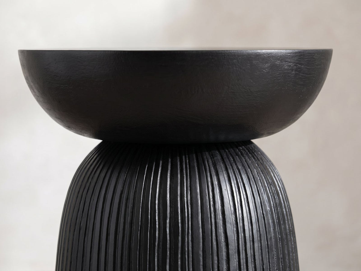 Close-up of the Stigliano Black Mango Bell Pedestal Side Table: the smooth bowl top resting on the grooved pedestal