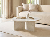 Stintino White Marble Coffee Table styled with books, a vase and a stone bowl in front of a cream sofa in a bright plaster room