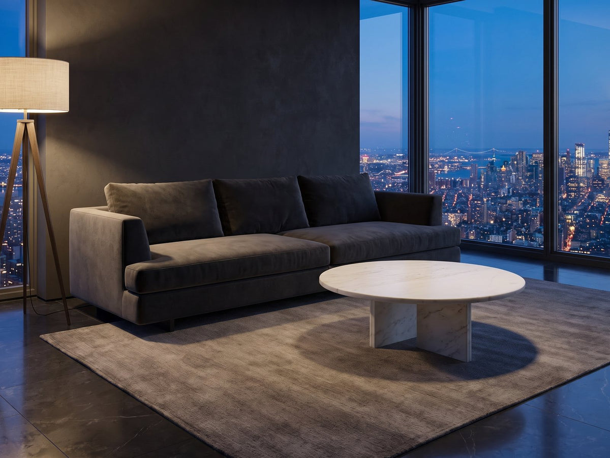 Stintino White Marble Coffee Table seen from the side, on a wool rug in front of a velvet sofa in a city penthouse at blue hour