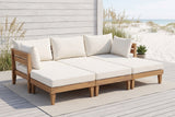 Stromboli acacia daybed set on a grey boardwalk deck at a Gulf Coast beach house, a whitewashed board wall and sea oats behind (rug and plant not included)