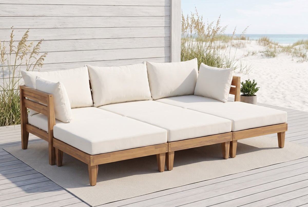 Stromboli acacia daybed set on a grey boardwalk deck at a Gulf Coast beach house, a whitewashed board wall and sea oats behind (rug and plant not included)