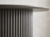 Close-up of the Strongoli 80-Inch Oval Fluted Pedestal Dining Set with 4 Chairs: a reeded half-drum pedestal under the slim edge of the charcoal oak top