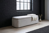 Subiaco gray storage bench under a tall steel-framed window against a charcoal-painted brick wall in a Chicago loft, with a folded off-white throw on the lid and a dried-stem vase beside it