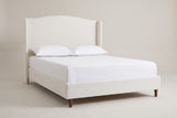 The Sulmona bed in ivory textured canvas with a white mattress and pillows (not included), three-quarter view on a light studio backdrop