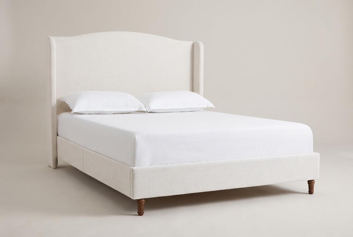 The Sulmona bed in ivory textured canvas with a white mattress and pillows (not included), three-quarter view on a light studio backdrop