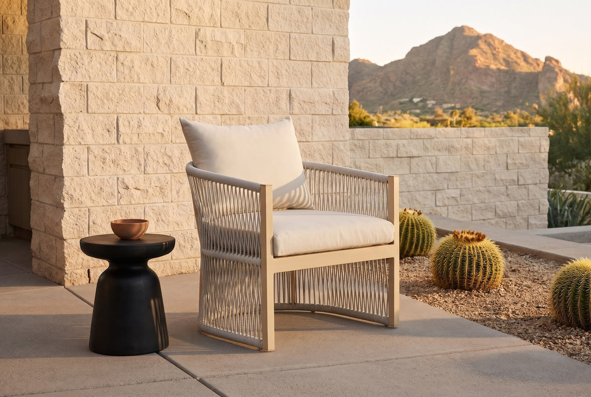 The Sutera rope lounge chair on a Paradise Valley patio of buff sandstone block and concrete pavers at golden hour, barrel cacti and Camelback Mountain behind