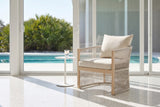 The Sutera rope lounge chair on a white terrazzo lanai in Sarasota beside a small white side table, glass sliders and a turquoise pool behind (side table not included)