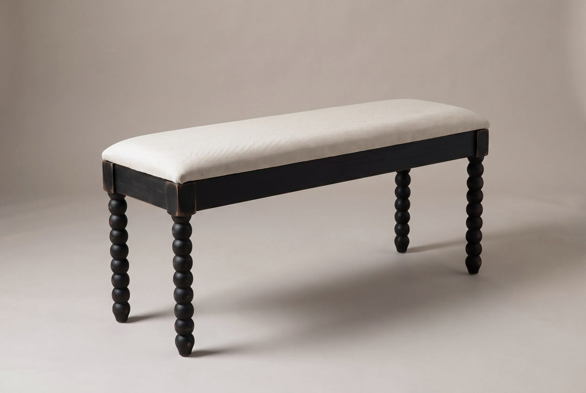 The Sutri bench in matte black with an oatmeal linen seat, three-quarter view on a light studio backdrop
