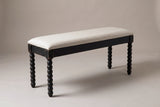 The Sutri bench in matte black with an oatmeal linen seat, three-quarter view on a light studio backdrop