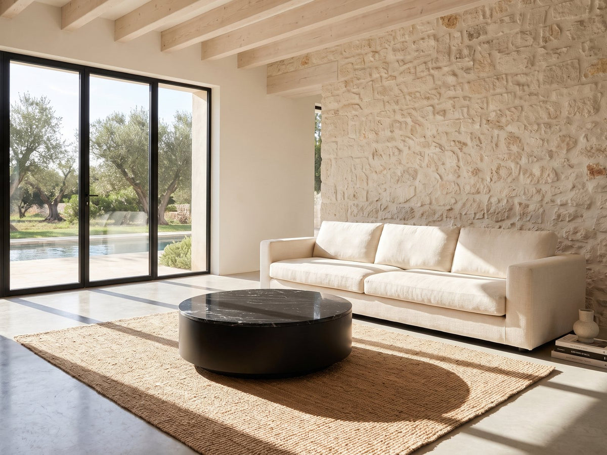 Taormina Black Marble Drum Coffee Table on a jute rug in front of a linen sofa in a poolside villa