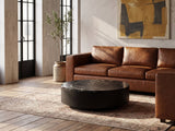 Taormina Black Marble Drum Coffee Table on a vintage rug in front of a leather sofa in an industrial loft