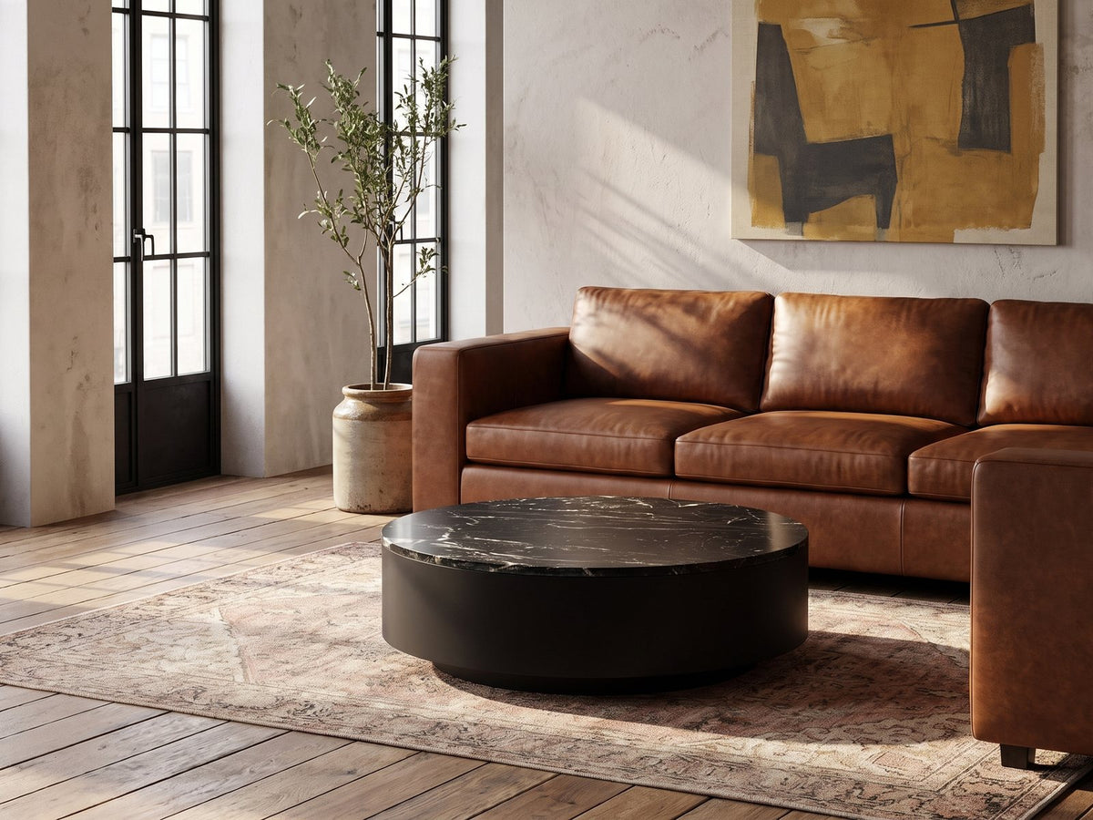 Taormina Black Marble Drum Coffee Table on a vintage rug in front of a leather sofa in an industrial loft