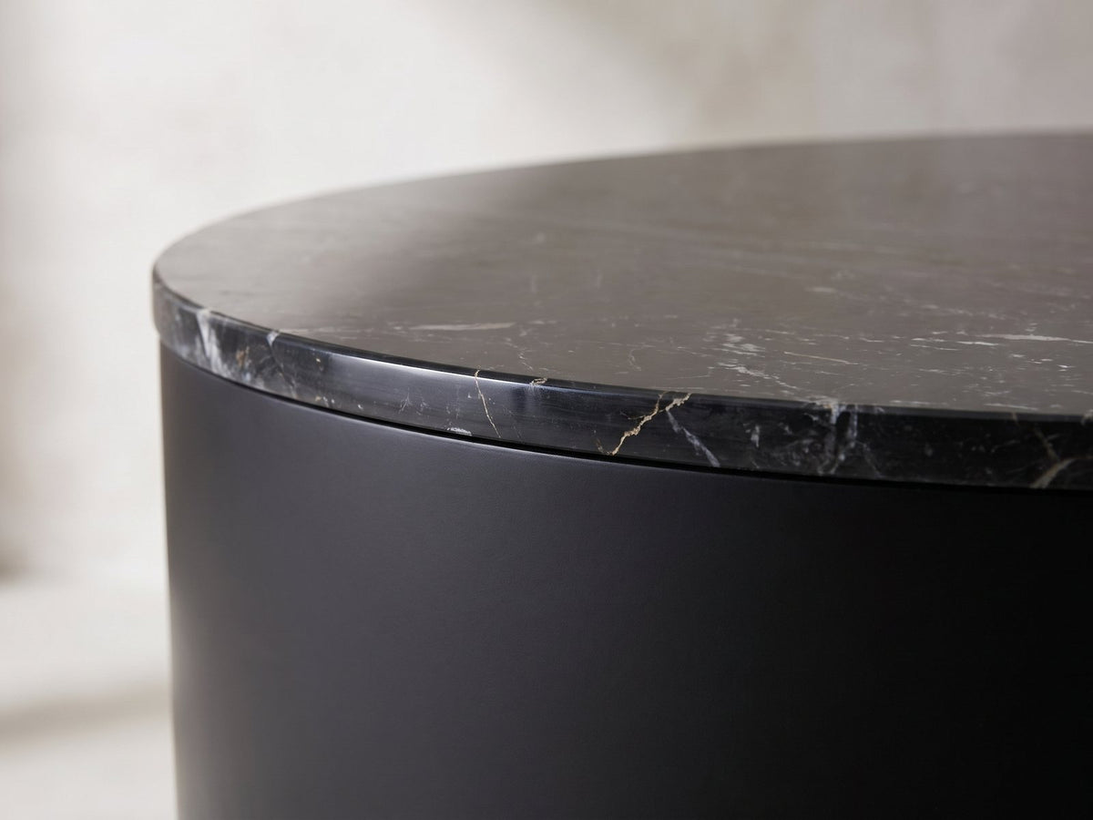 Close-up of the Taormina Black Marble Drum Coffee Table: the polished marble top edge over the matte-black drum