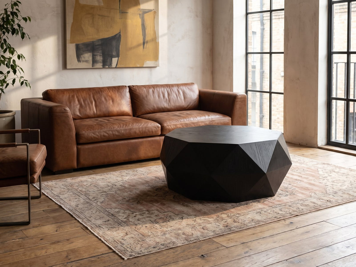 Taranto Black Faceted Drum Coffee Table on a vintage rug in front of a leather sofa in an industrial loft
